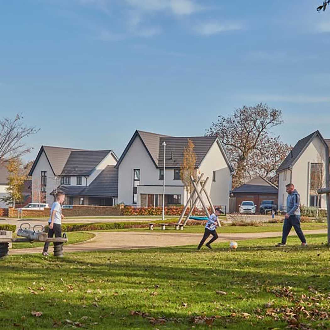 dad and sons playing football in the park