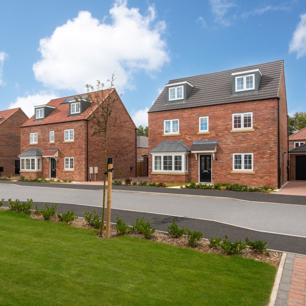 Modern red‑brick detached homes at Cygnet View in Swanland, shown along a newly built residential street with landscaped front gardens.