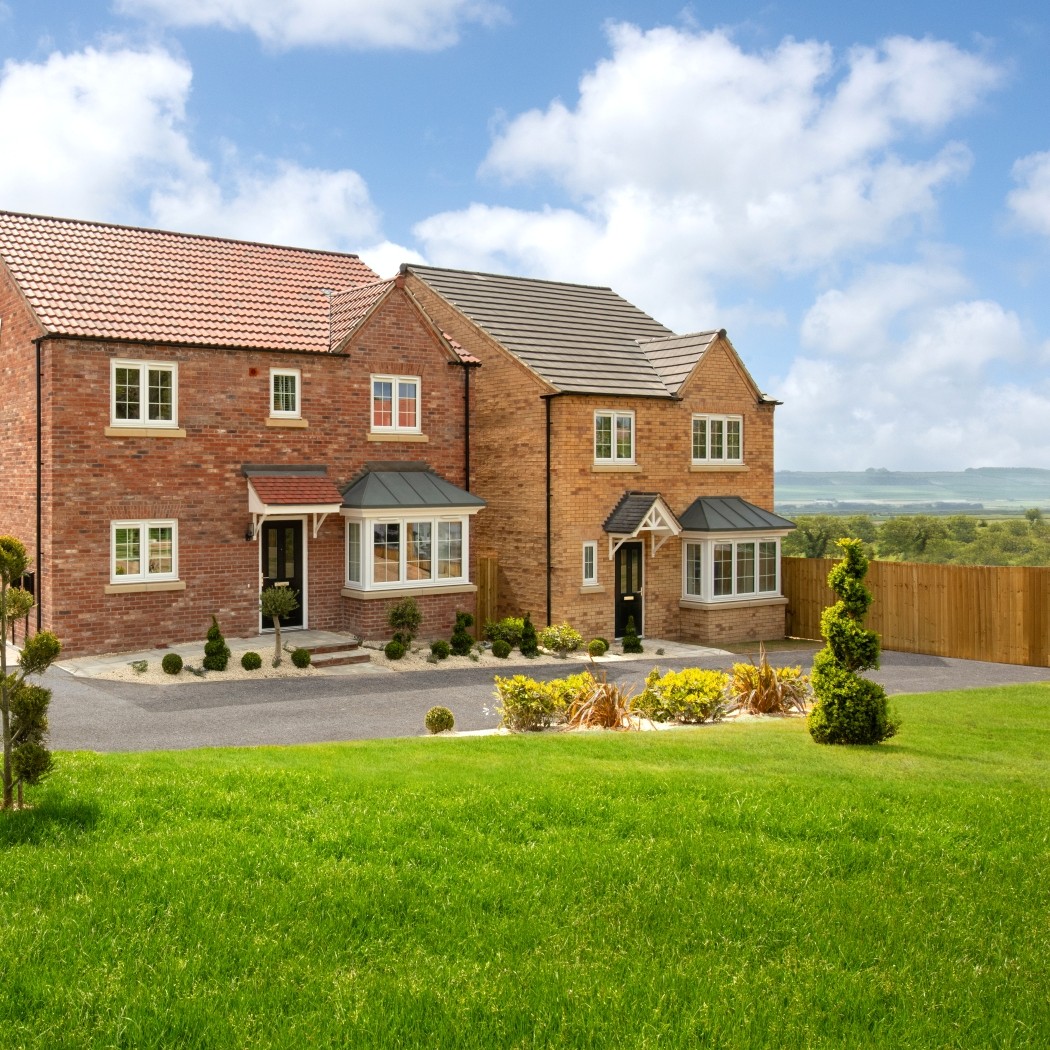 Modern red‑brick detached homes at Meadow Fields in East Ayton, North Yorkshire, overlooking landscaped gardens and open countryside views.