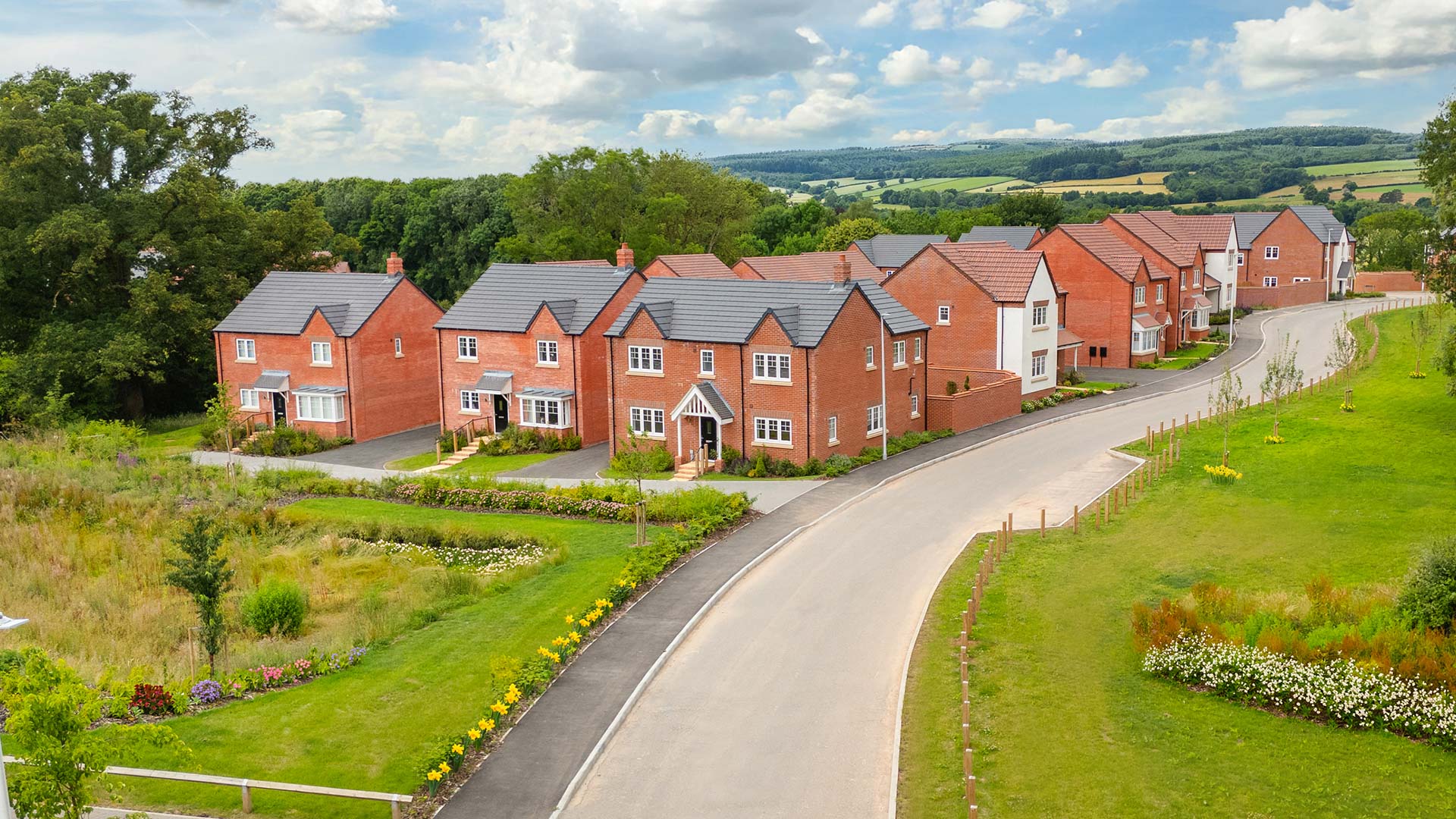Street scene drone photography taken at Ludlow Green - featuring detached homes overlooking green open space.