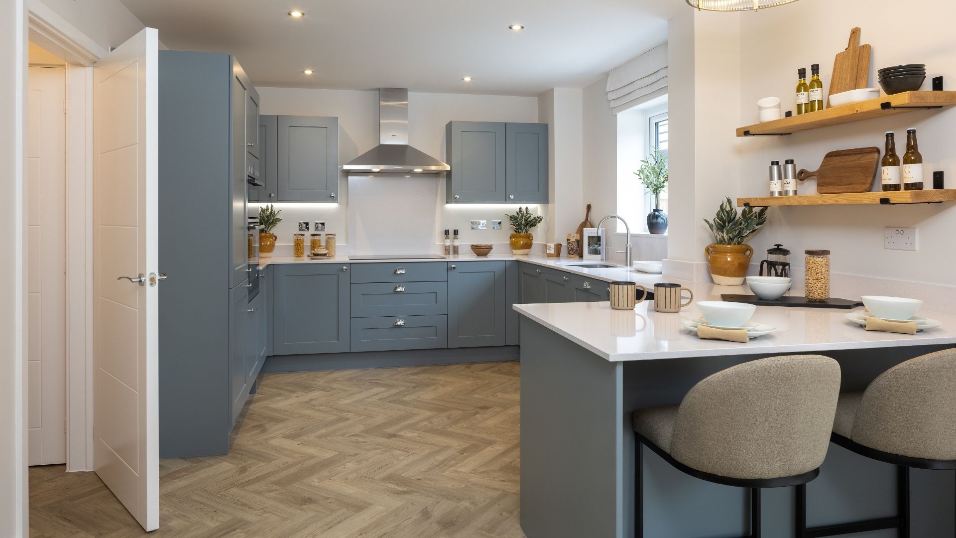 Bright contemporary kitchen in a typical Crest Nicholson home, with Silestone work surfaces, shaker cabinetry and a relaxed breakfast bar designed for effortless everyday family living.