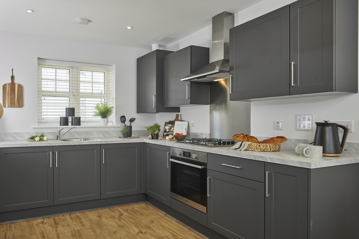 Open-plan kitchen and dining area in a Crest Nicholson home featuring dark grey cabinetry, and a grey worktop.