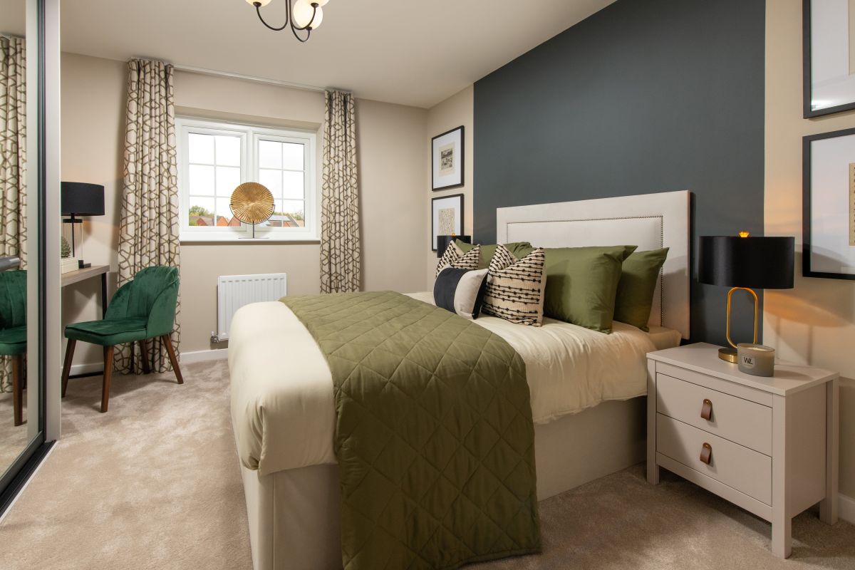 Light filled bedroom featuring double bed and dressing table next to a mirrored, fitted wardrobe