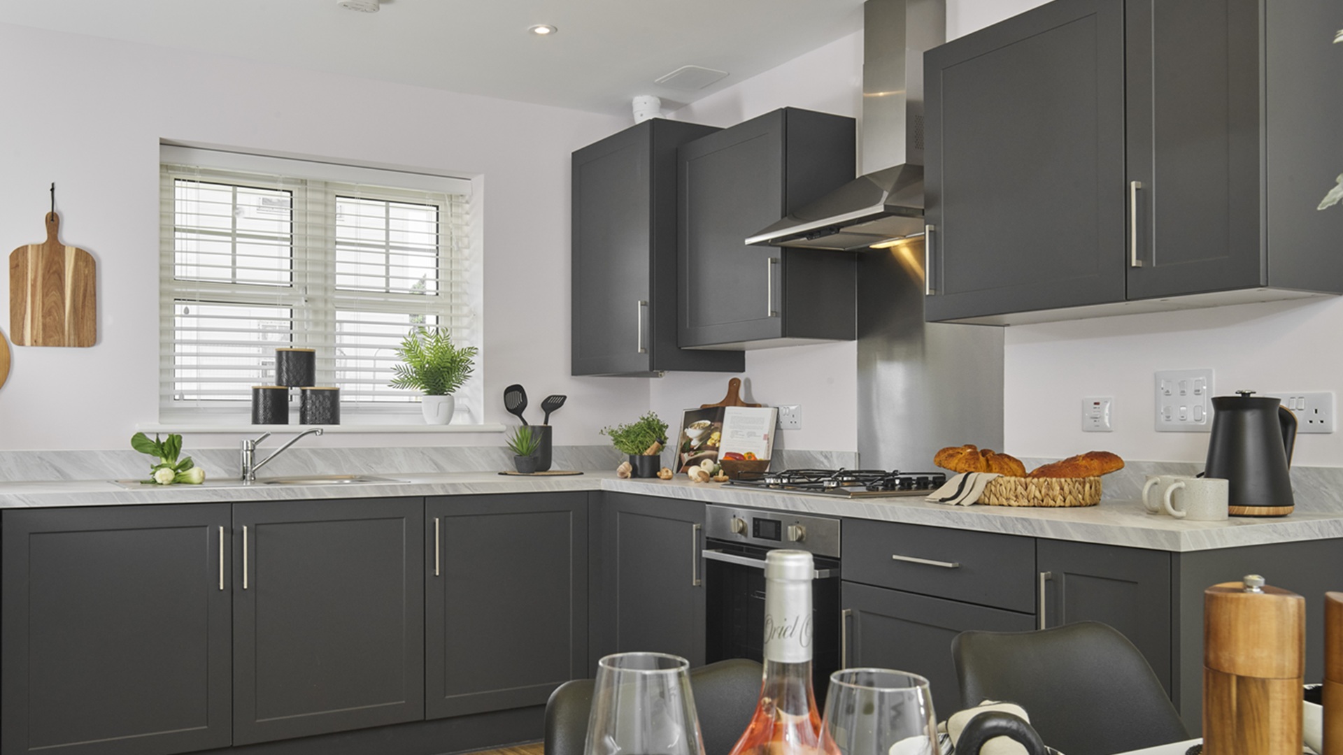 Open-plan kitchen and dining area in a Crest Nicholson home featuring dark grey cabinetry, and a grey worktop.