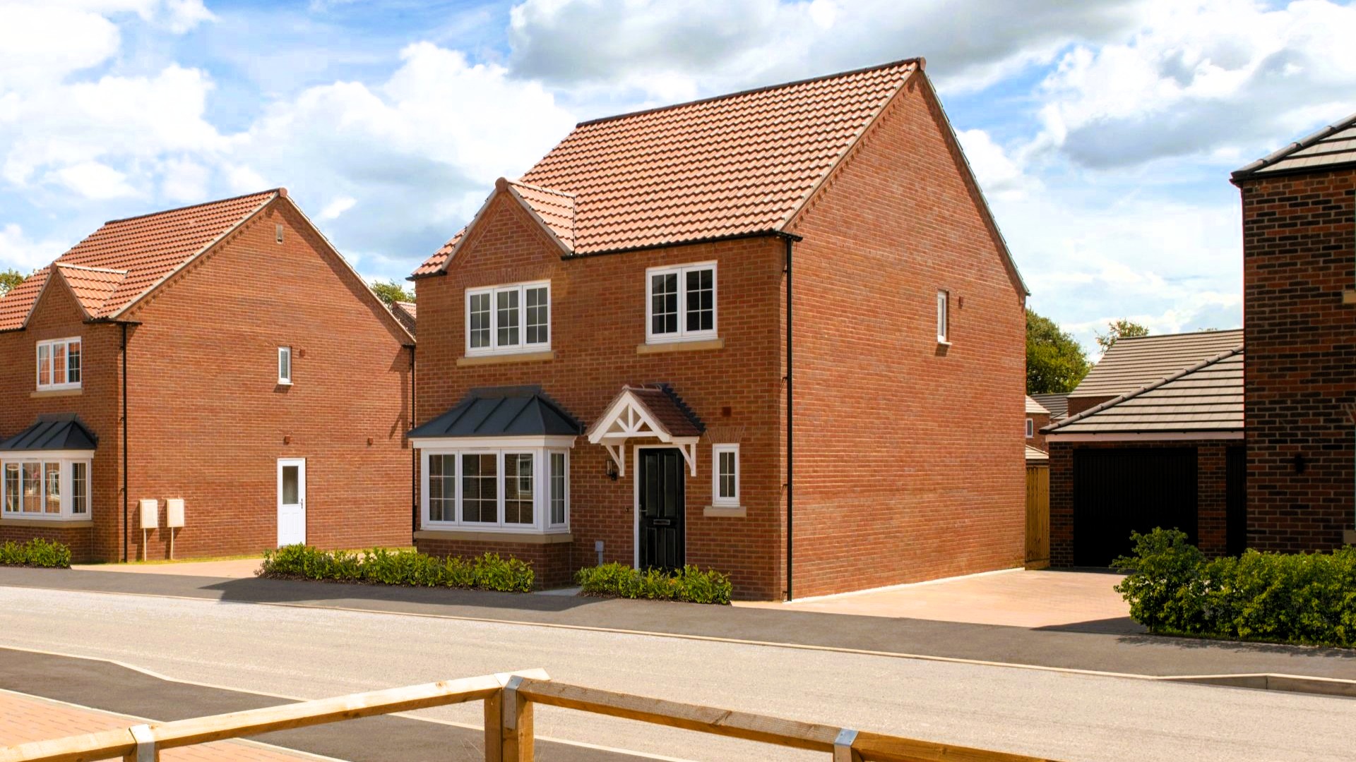 Front elevation of a detached red-brick family home with bay window, private driveway and detached garage