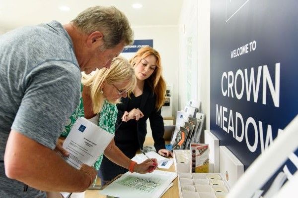 Prospective homebuyers talking with Crest Nicholson sales executive at Crown Meadows in Faversham