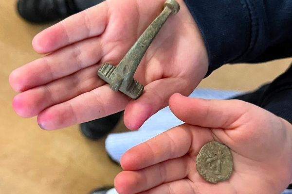 children's hands holding coin and brooch