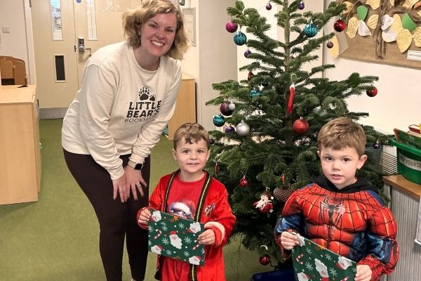 Emily from Little Bears Bookshop giving wrapped presents to two boys