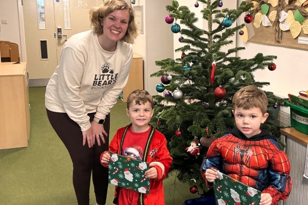 Emily from Little Bears Bookshop giving wrapped presents to two boys